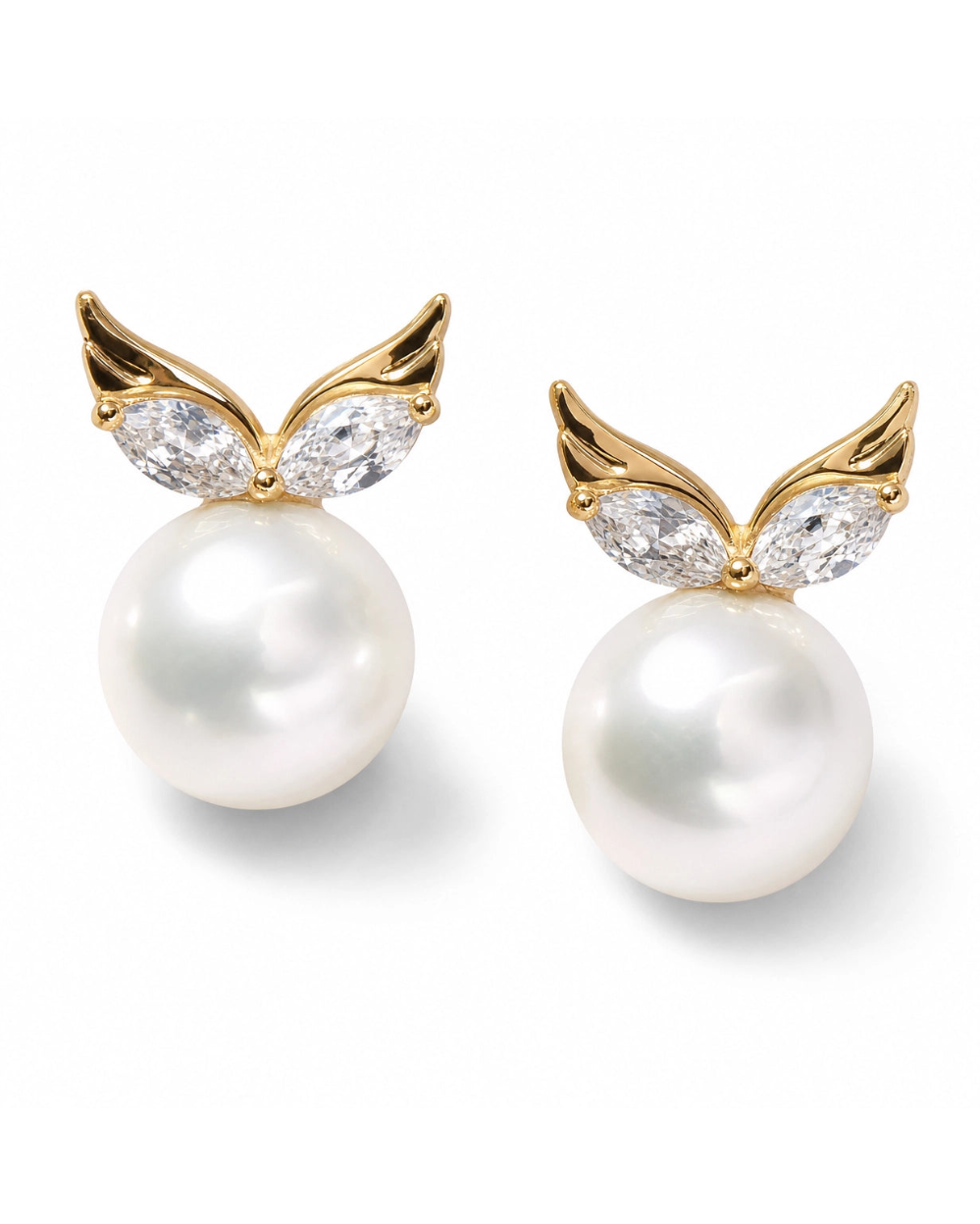Pearl earrings with gold wing-like designs and clear gemstones on a white background