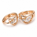 Pair of rose gold heart-shaped rings with clear gemstones on a white background